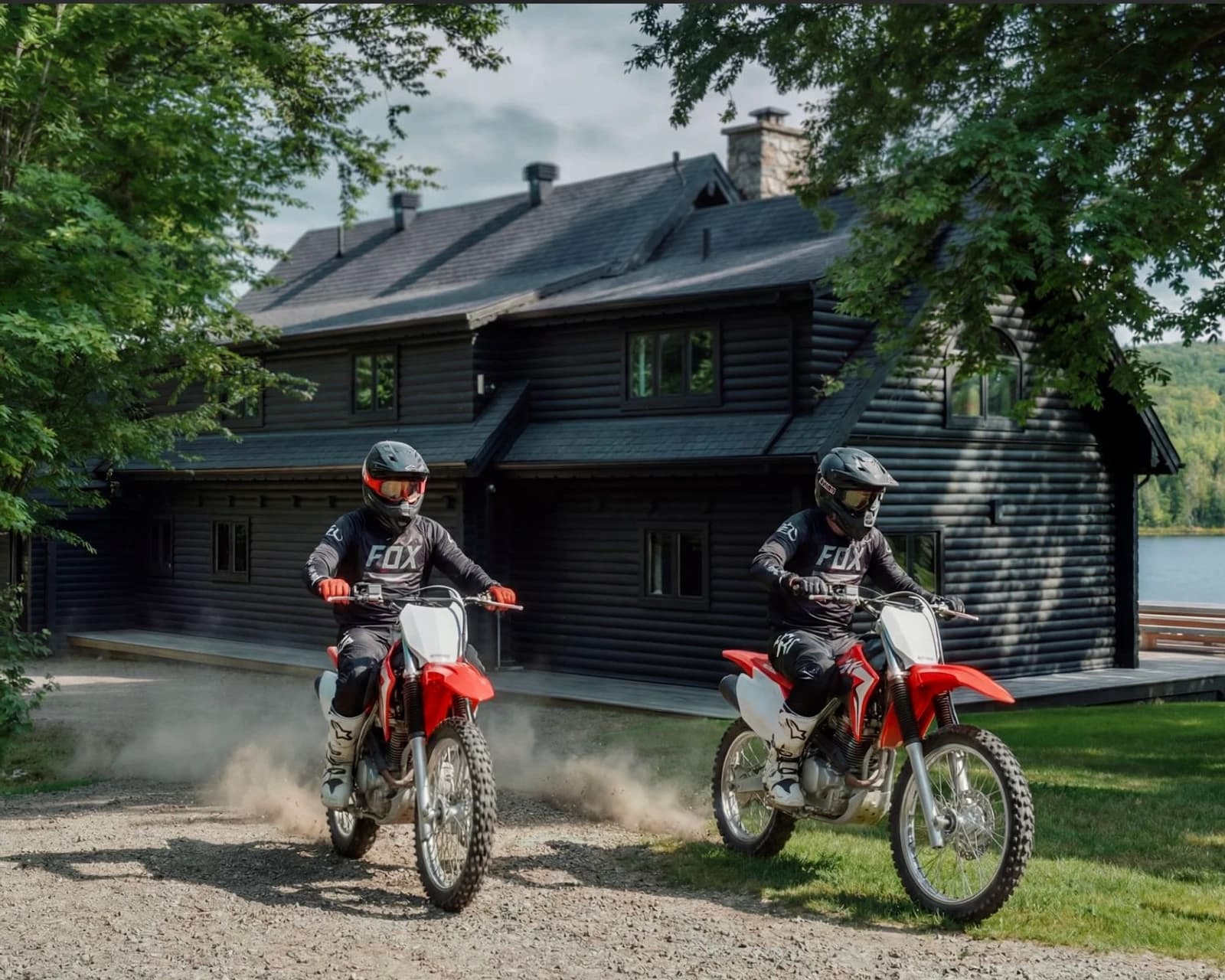 Two motocross riders kicking up dust on forest trails