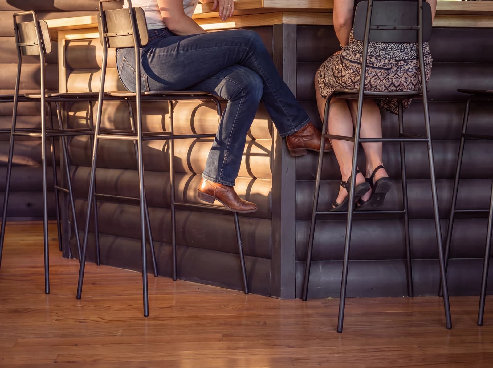 Two guests seated at the bar, detail crop of stools and counter