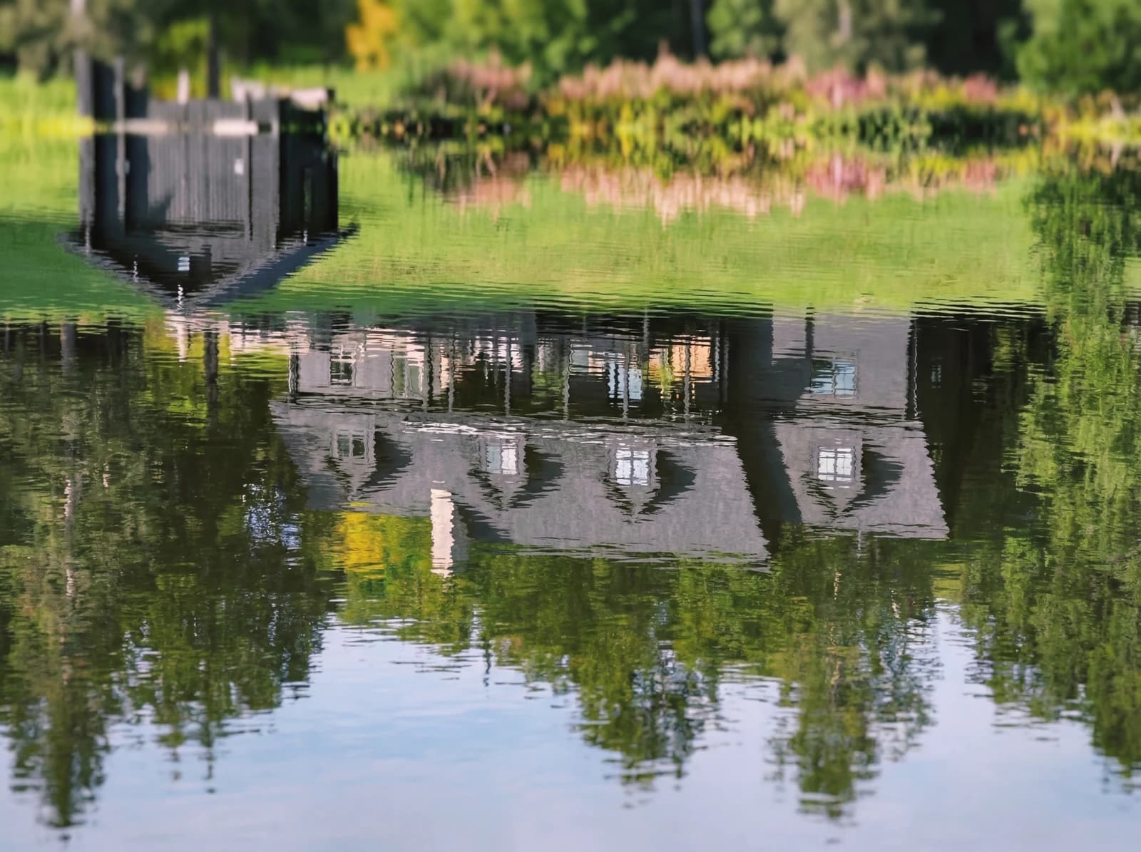 Méchante Cabane mirrored in the still lake water, forest and sky reflected on the surface