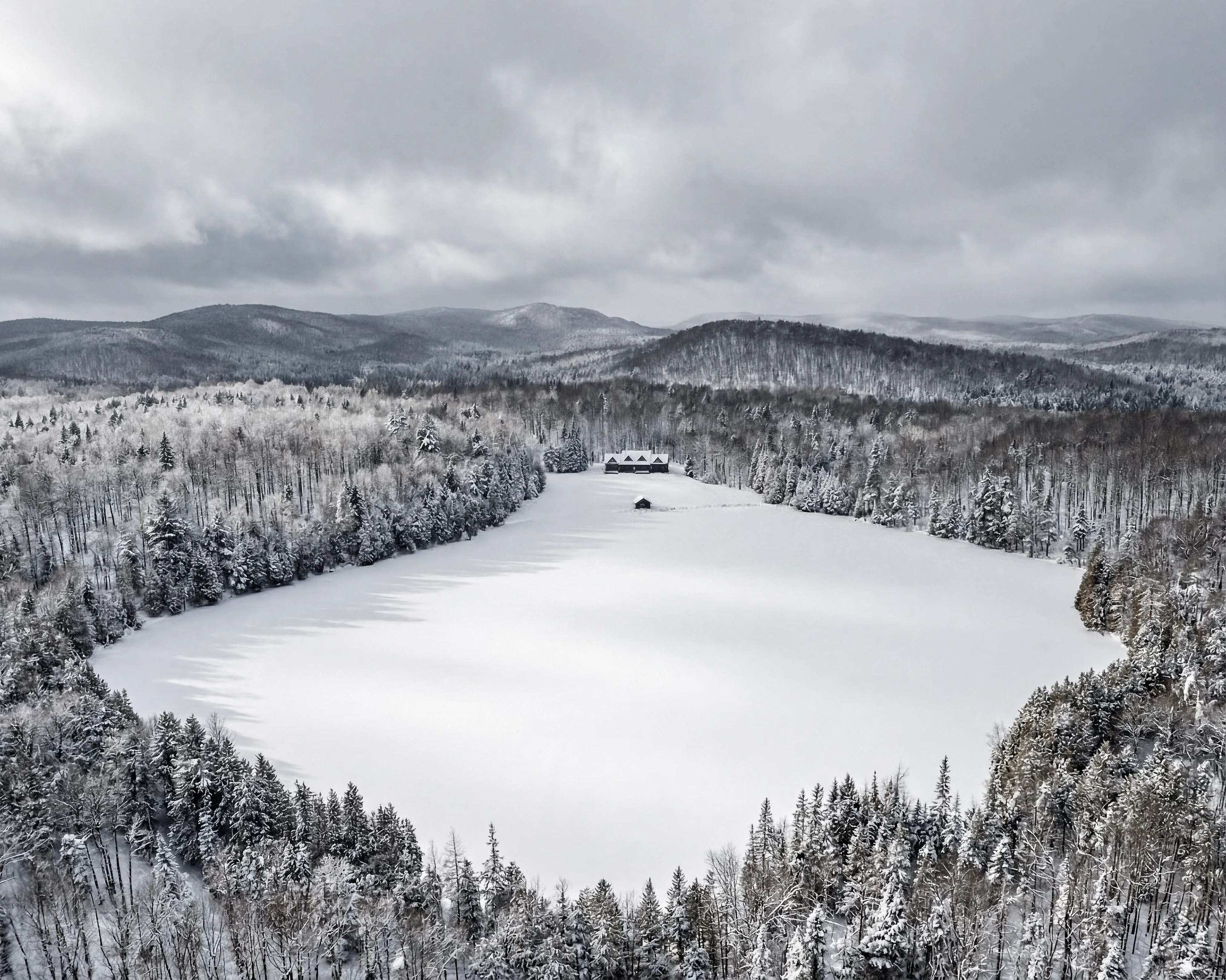 Méchante Cabane — winter aerial view of the frozen lake, the chalet and surrounding mountains